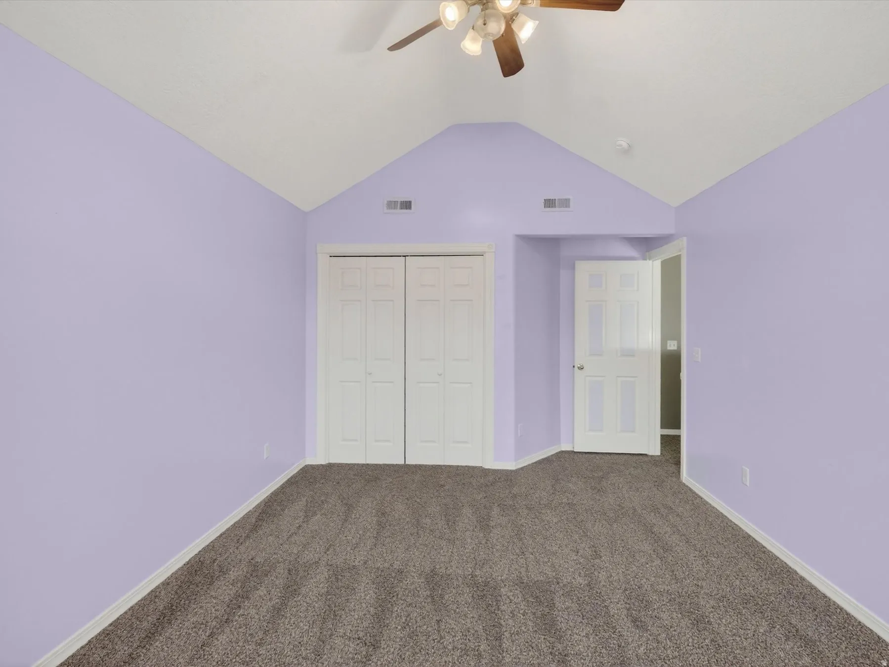 Unfurnished bedroom with a closet, dark carpet, and a ceiling fan