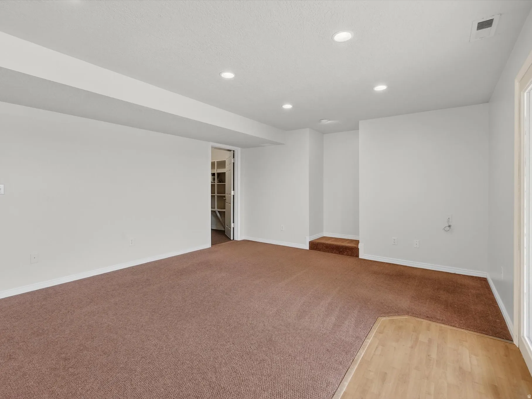 Unfurnished room with recessed lighting, light wood-style floors, and light colored carpet