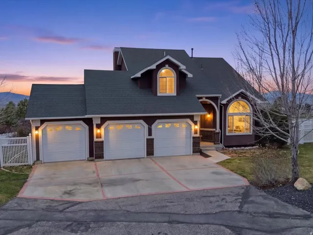 Traditional home with roof with shingles, a garage, concrete driveway, and a mountain view
