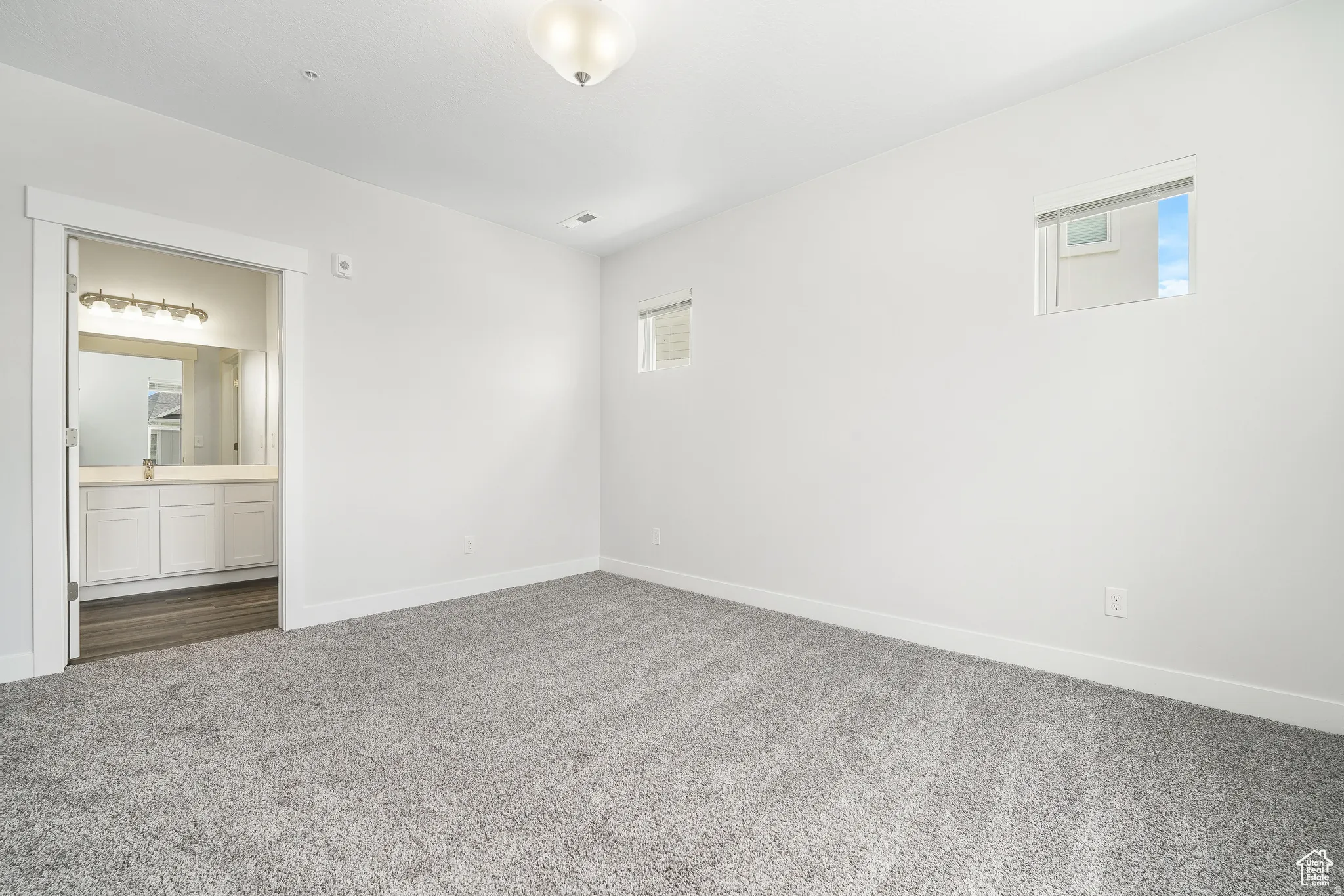 Unfurnished bedroom featuring dark carpet and connected bathroom