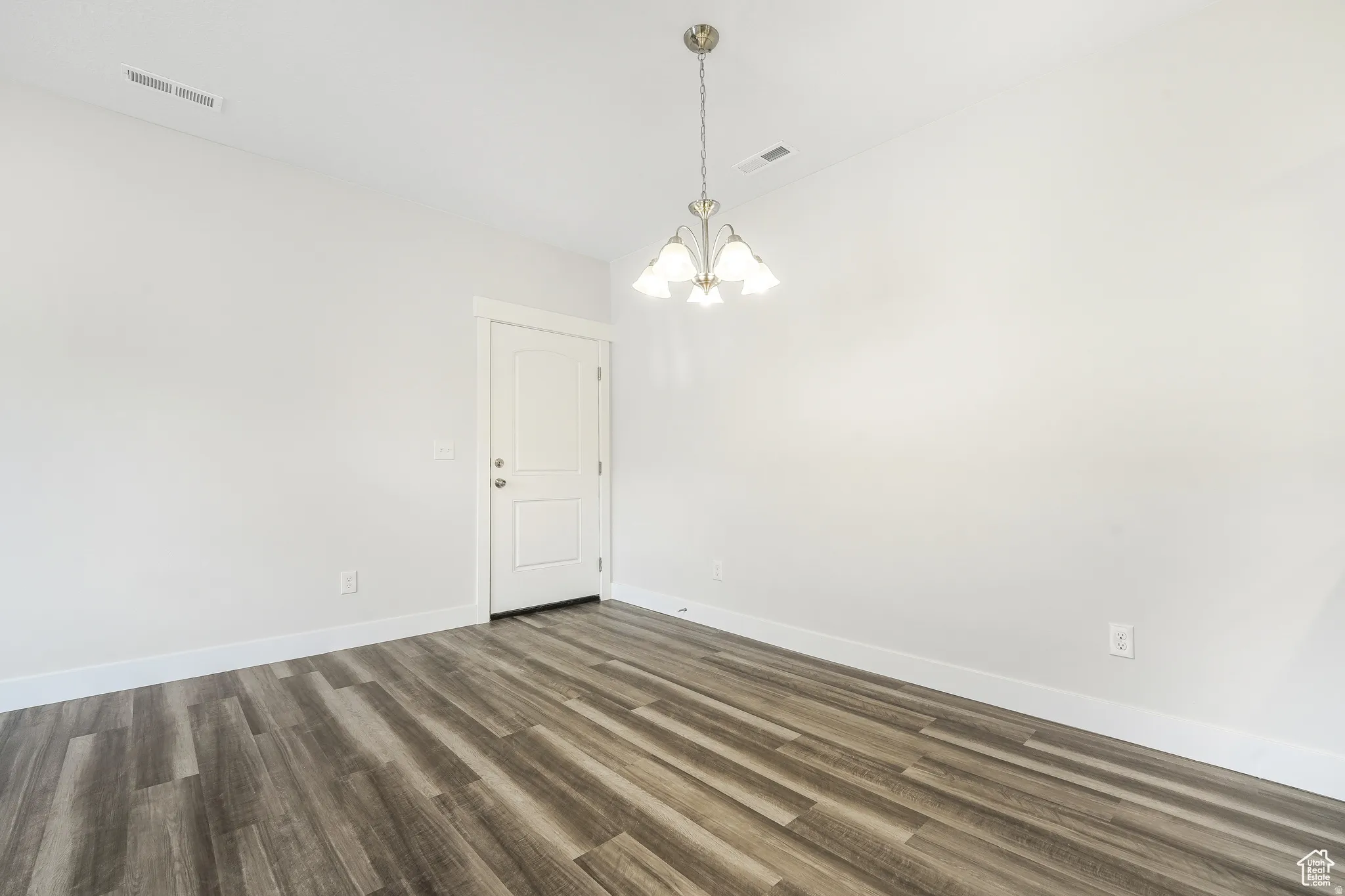 Unfurnished room with dark wood-style floors and a chandelier