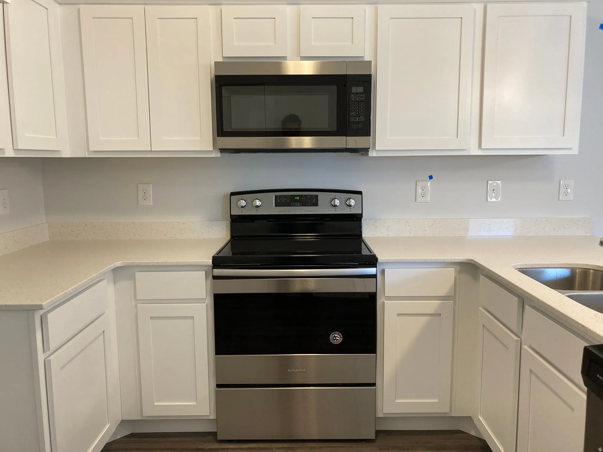 Kitchen featuring stainless steel appliances, white cabinets, and light stone counters