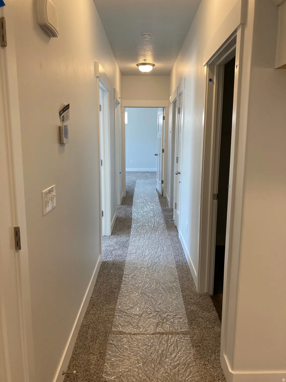 Corridor featuring dark colored carpet and baseboards