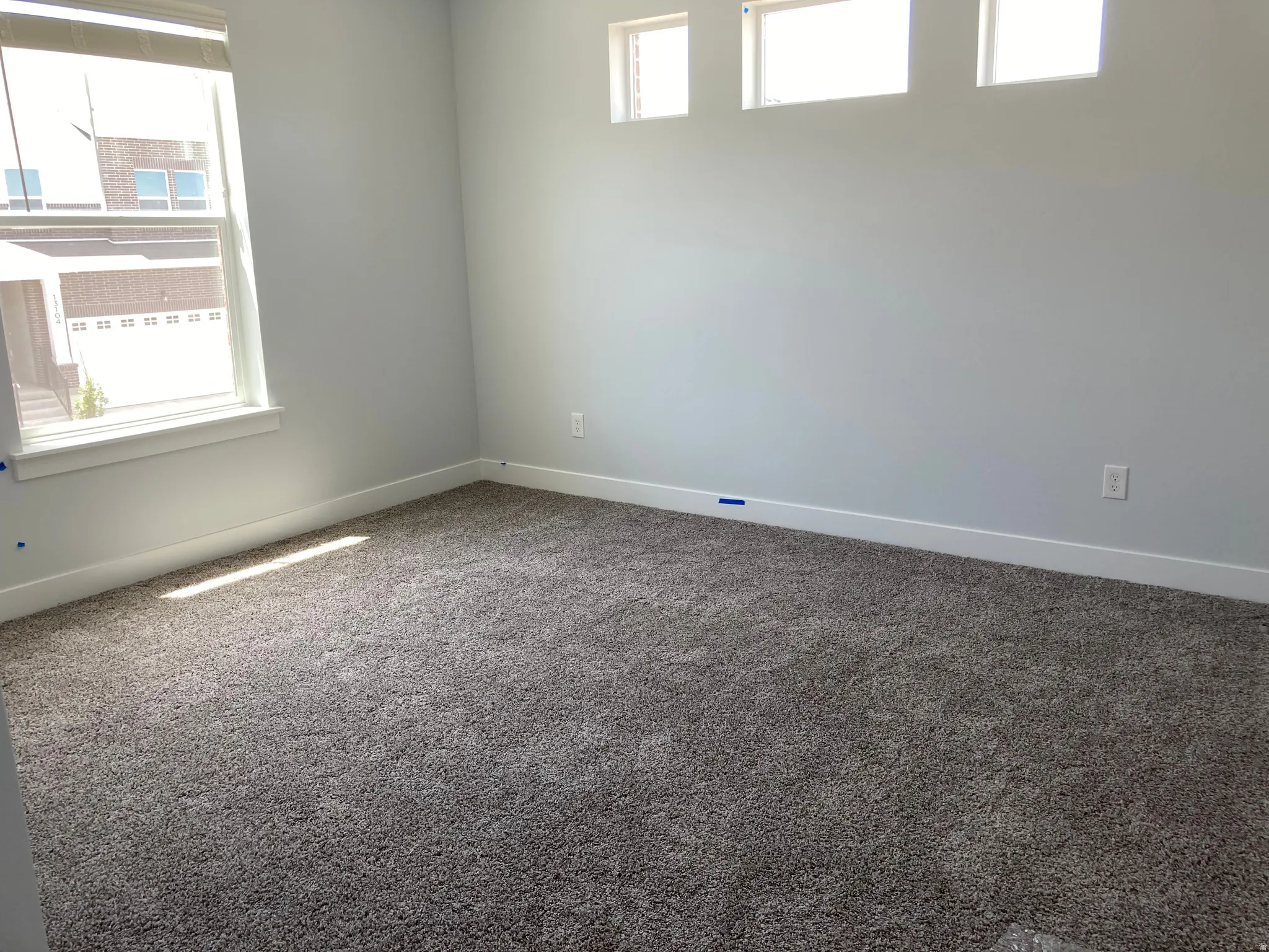 Empty room with plenty of natural light and dark carpet