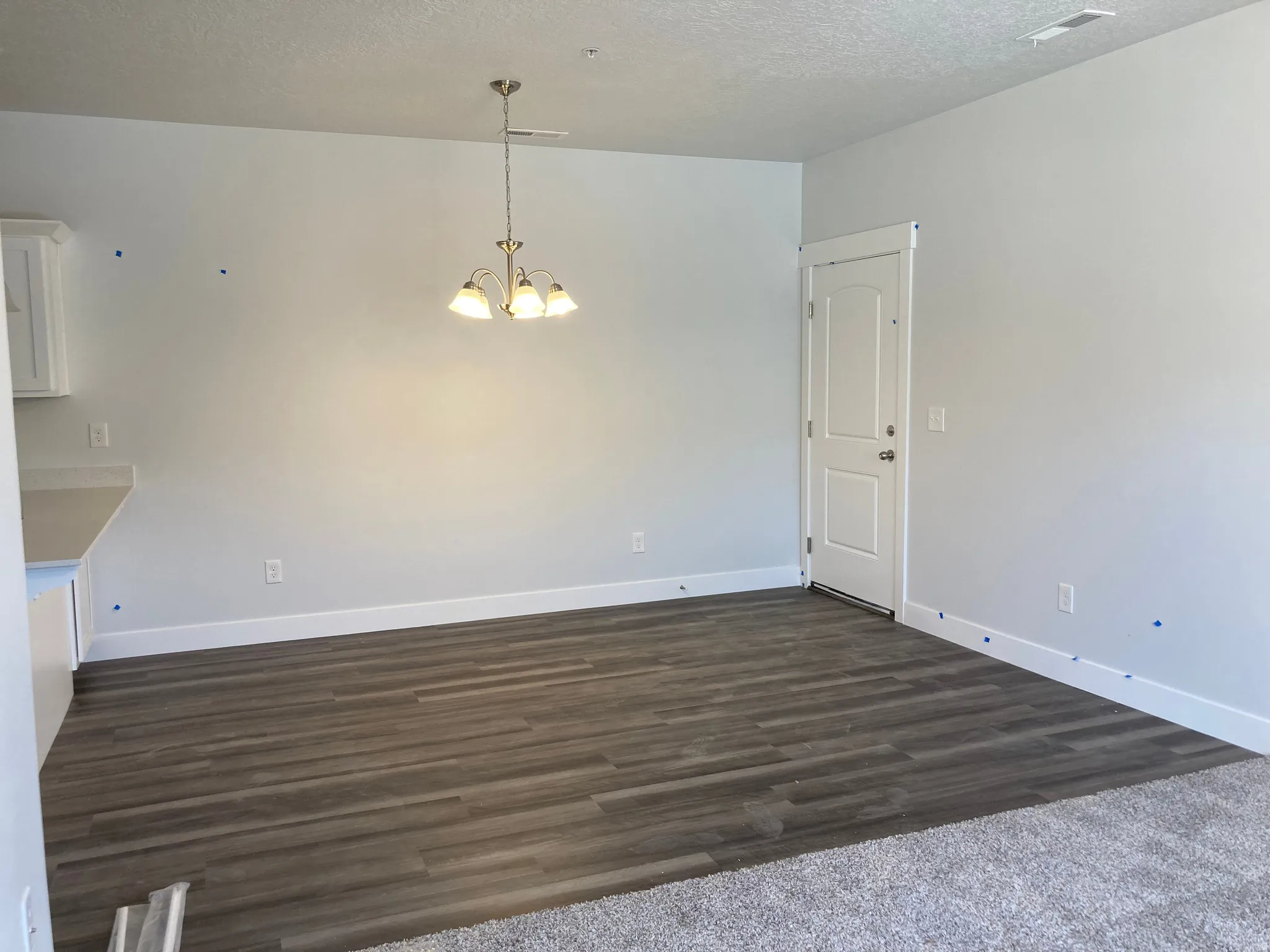 Unfurnished dining area with hanging lights, a textured ceiling, and dark wood-style flooring