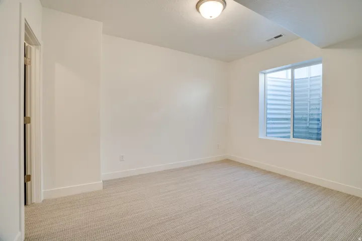 Empty room featuring light colored carpet and a textured ceiling