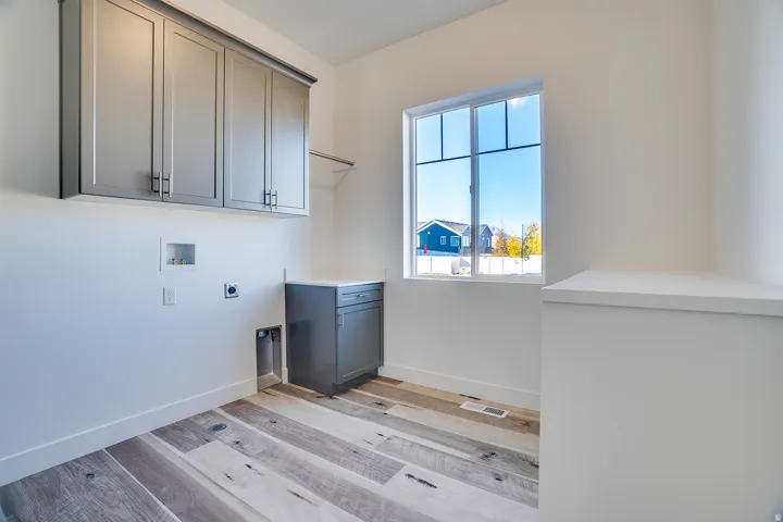 Laundry area featuring hookup for a washing machine, electric dryer hookup, cabinet space, and light wood finished floors