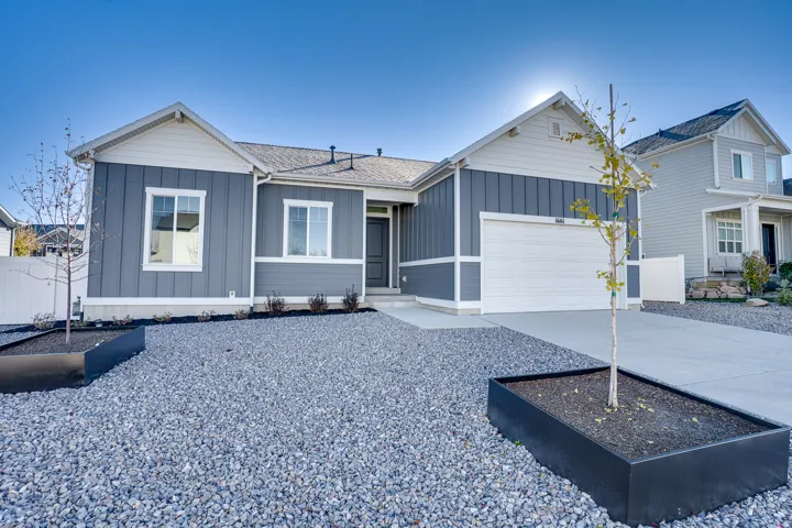 View of front of home with board and batten siding, driveway, an attached garage, and a shingled roof