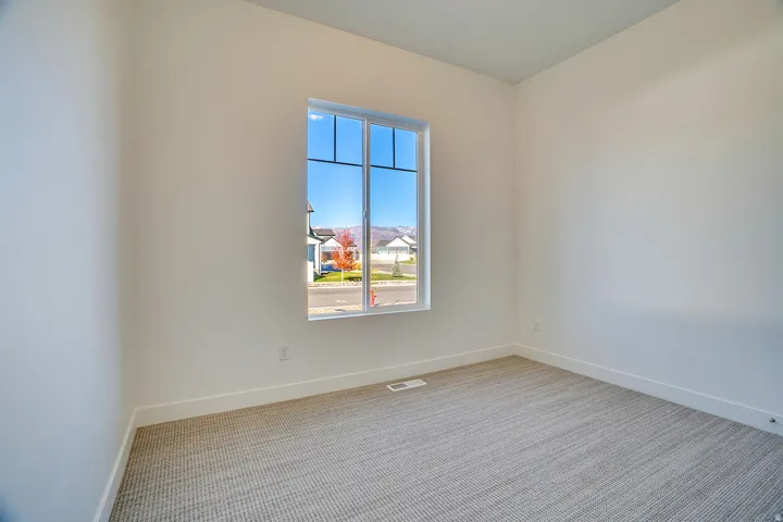 Spare room featuring light colored carpet and baseboards