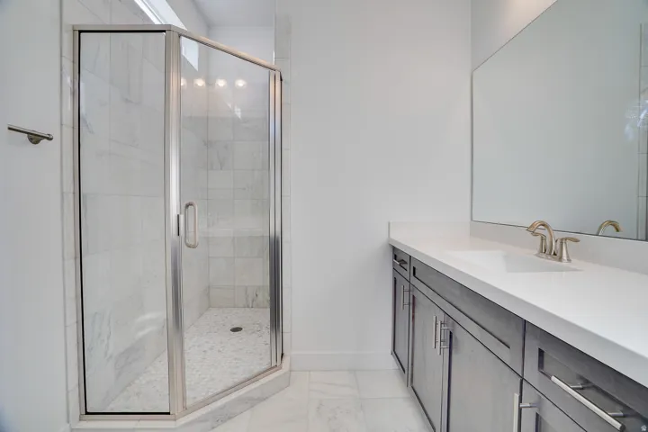 Bathroom with vanity, a shower stall, and light marble finish floors