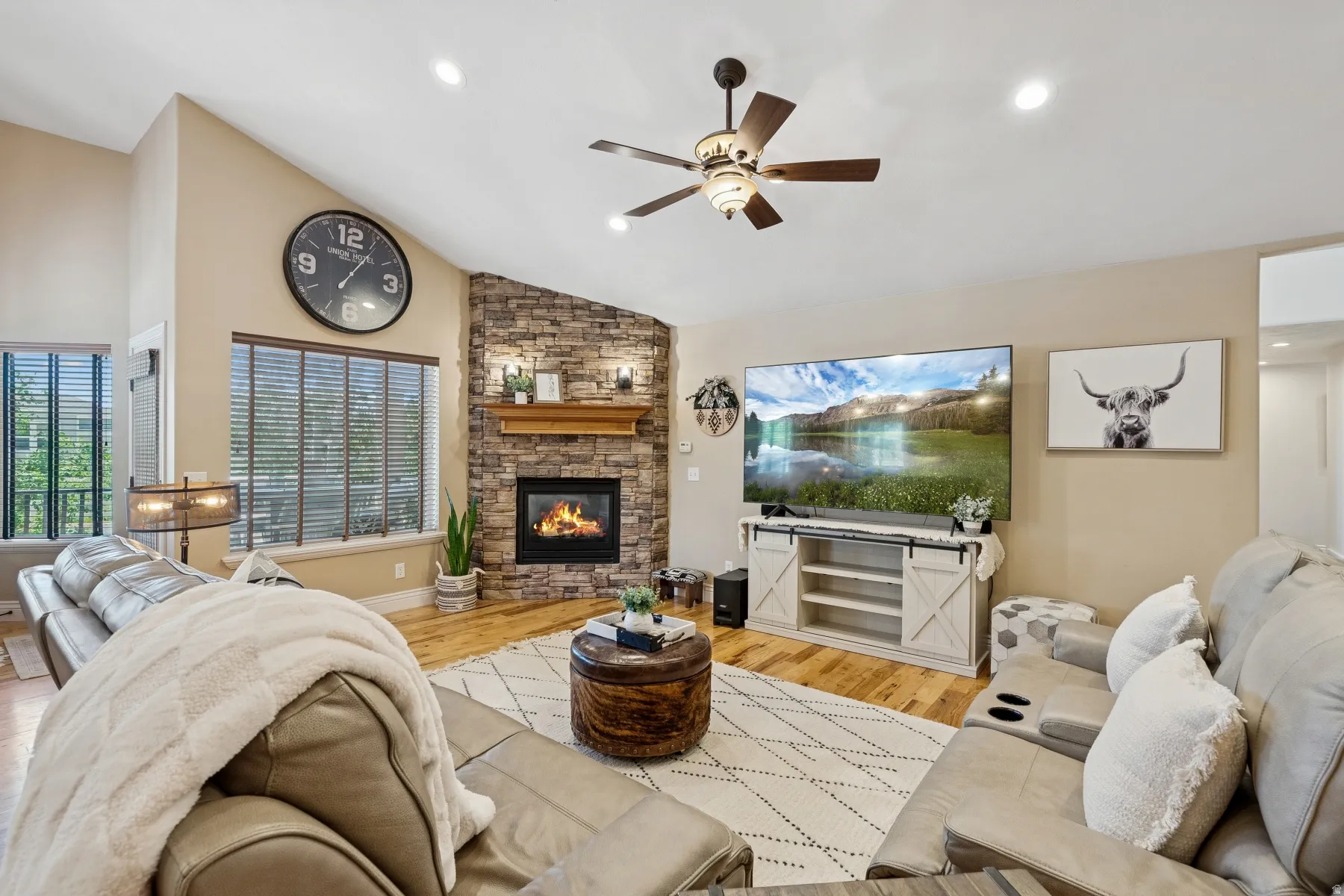 Living room with a ceiling fan, light wood finished floors, vaulted ceiling, a fireplace, and recessed lighting