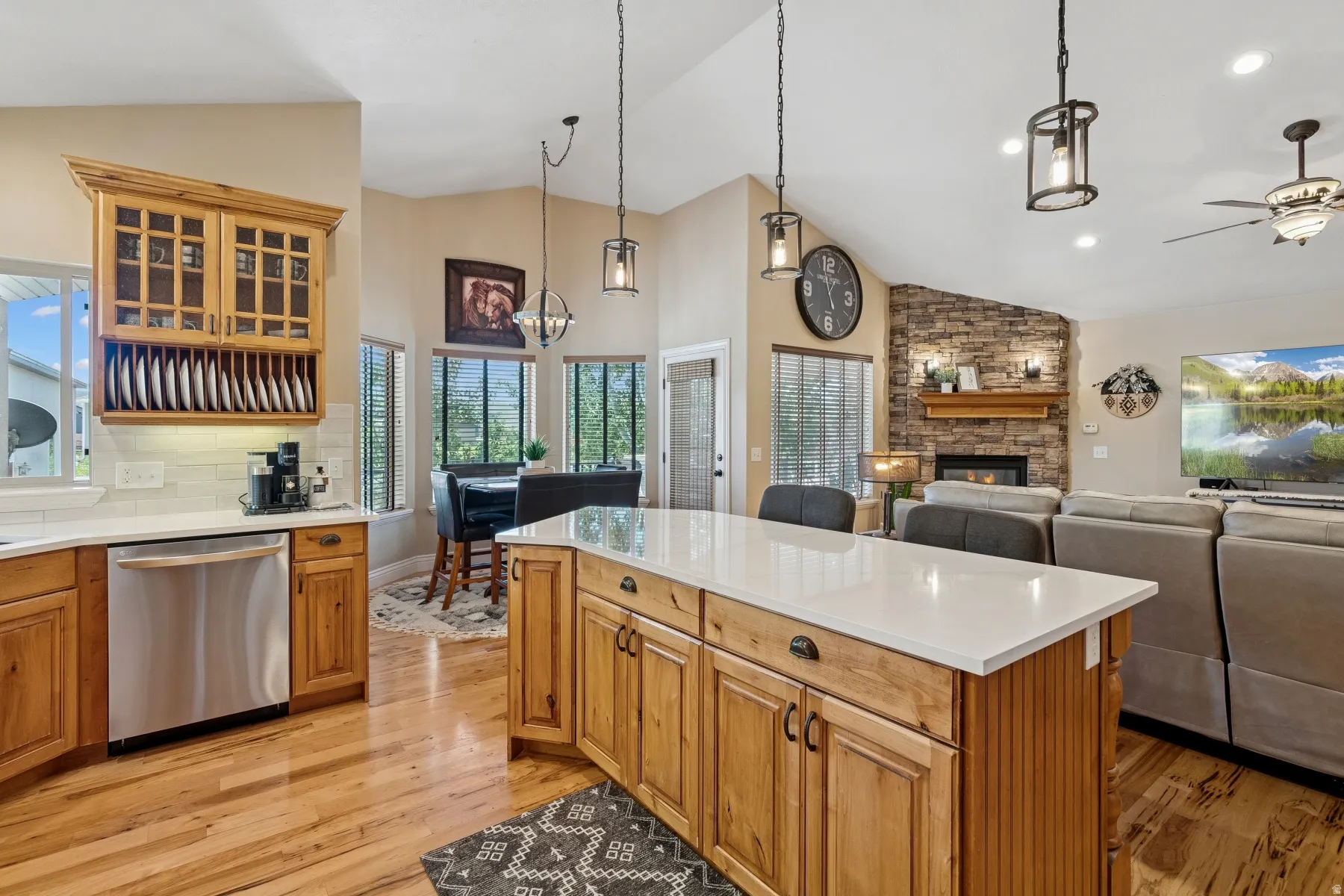 Kitchen featuring dishwasher, glass fronted cabinets, a fireplace, a kitchen island, and light wood finished floors