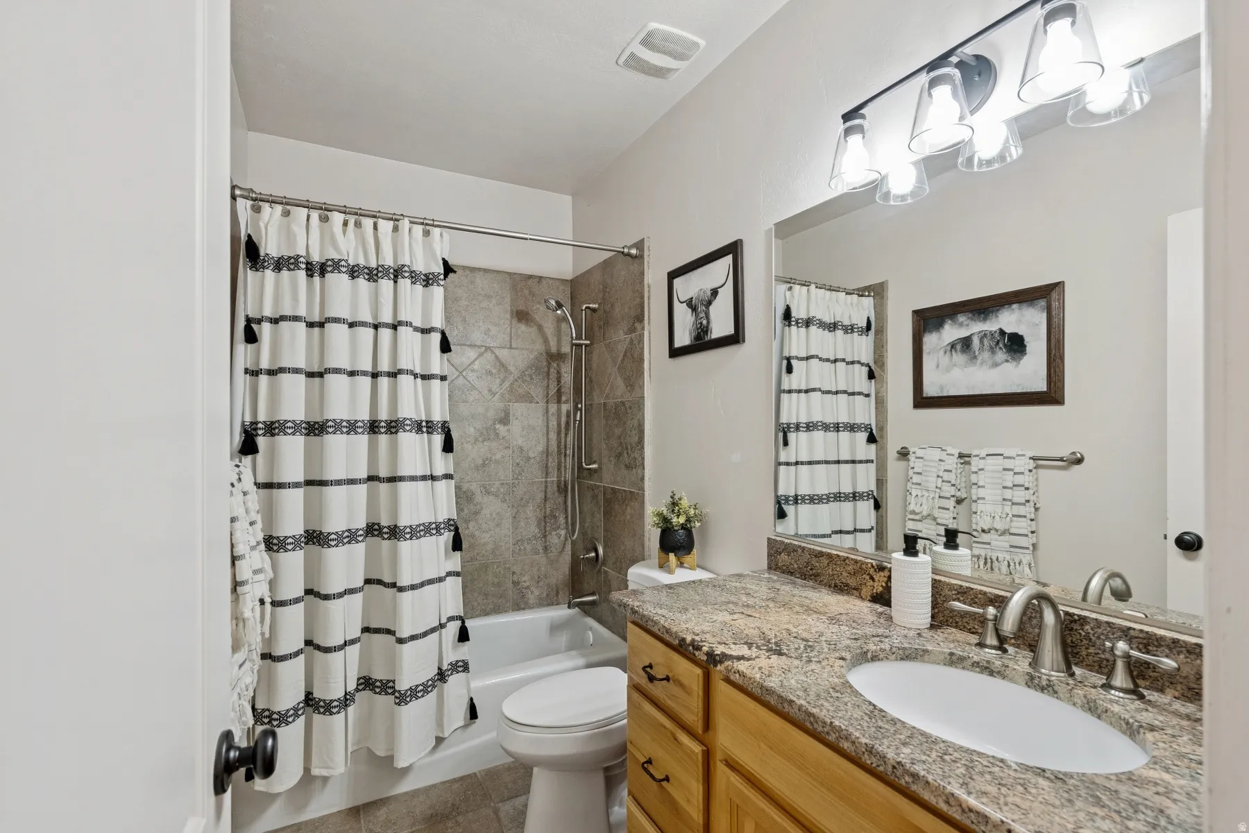 Full bathroom with vanity, shower / tub combo with curtain, and light tile patterned flooring