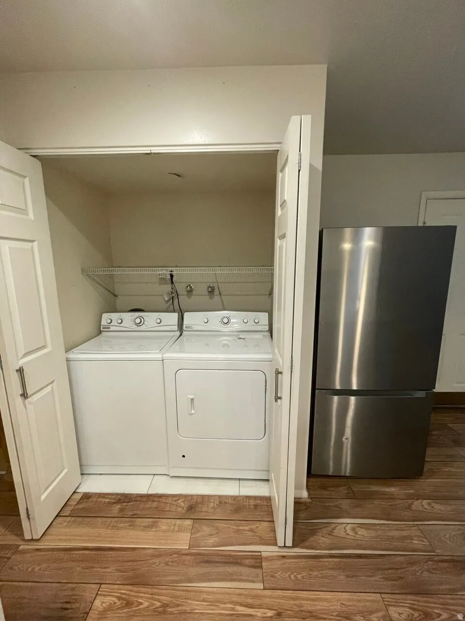 Laundry area with hardwood / wood-style floors and washing machine and clothes dryer