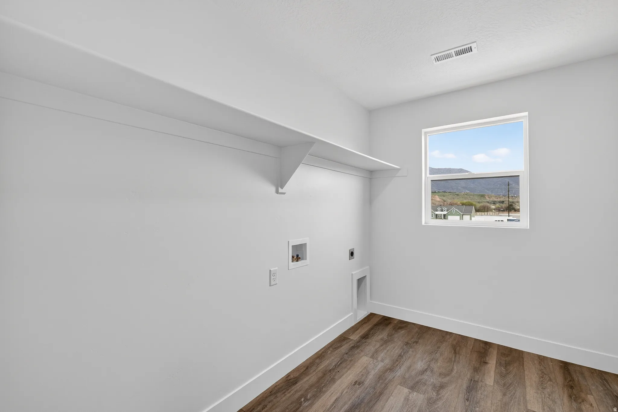 Laundry area featuring wood finished floors, hookup for an electric dryer, and washer hookup