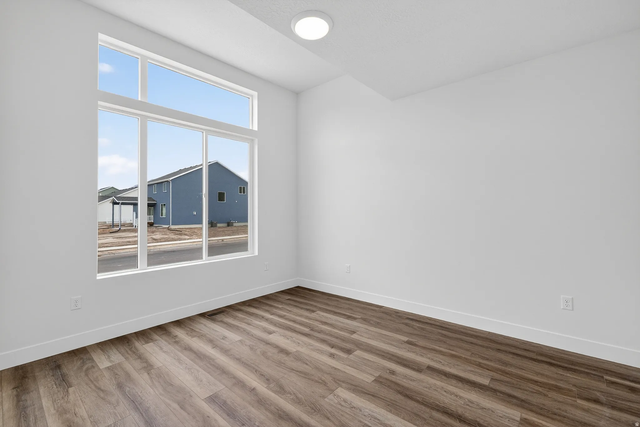Empty room with light wood-style flooring and lofted ceiling