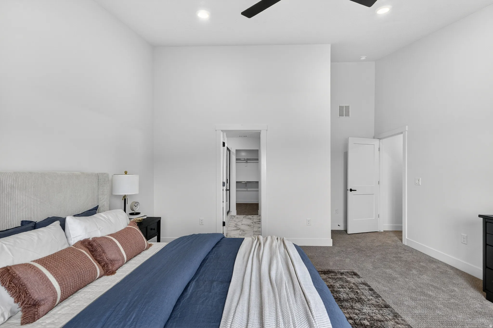 Carpeted bedroom with a high ceiling, a walk in closet, recessed lighting, and ceiling fan