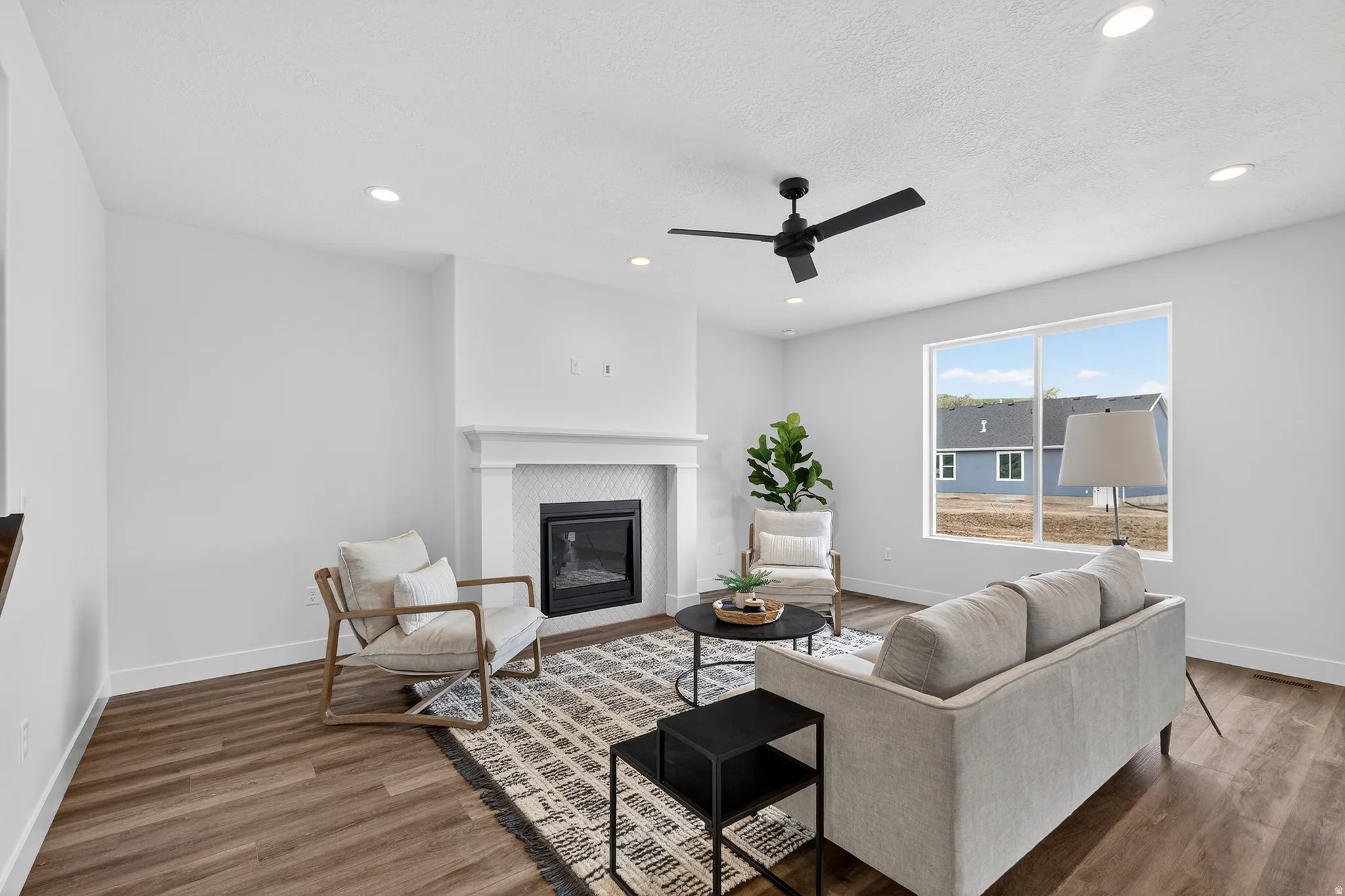 Living area with wood finished floors, a ceiling fan, recessed lighting, a glass covered fireplace, and a textured ceiling
