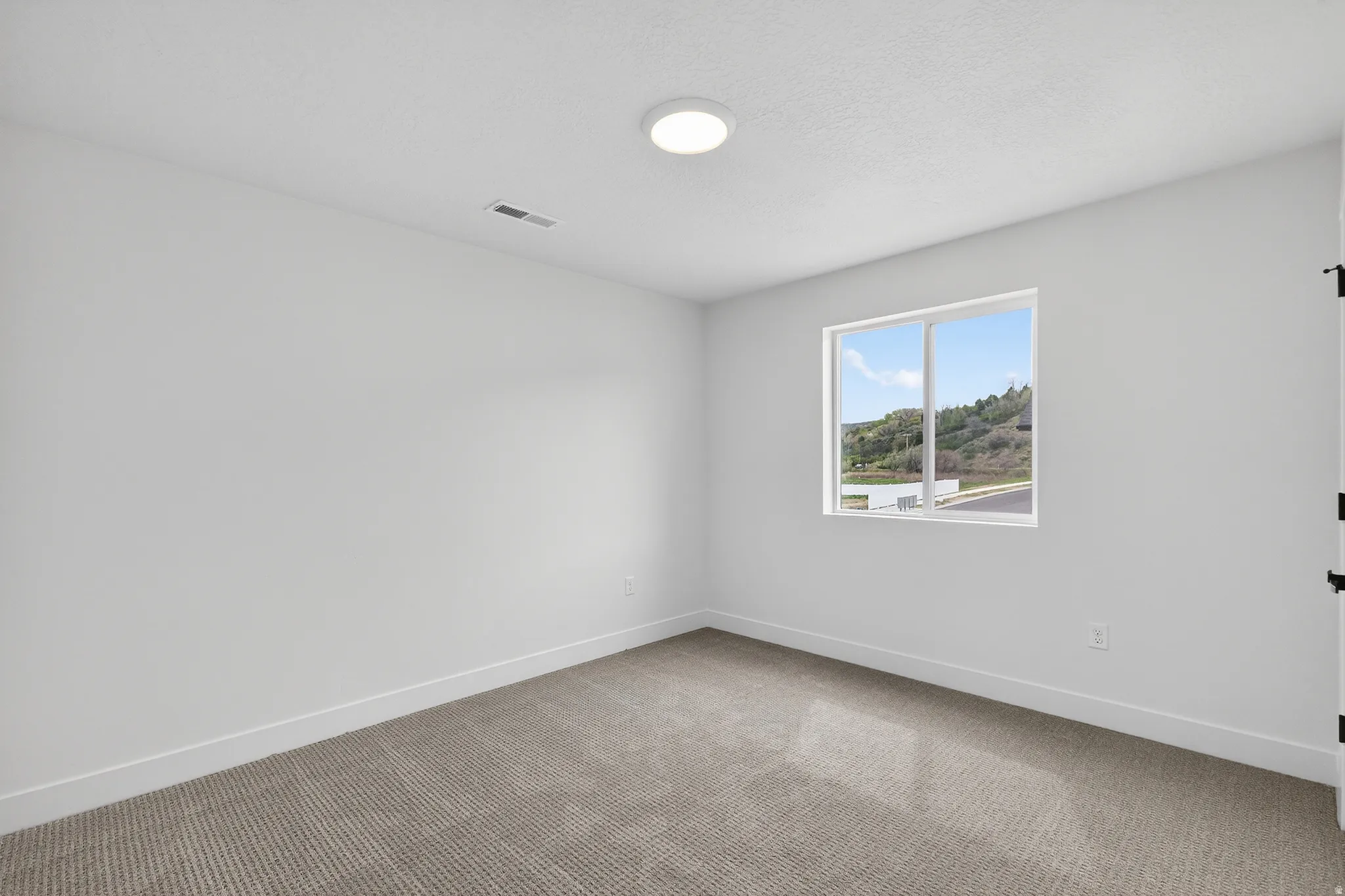 Spare room featuring light carpet and baseboards