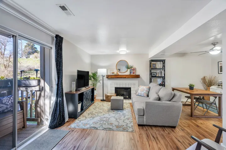 Living room featuring a tiled fireplace, light wood finished floors, and a ceiling fan