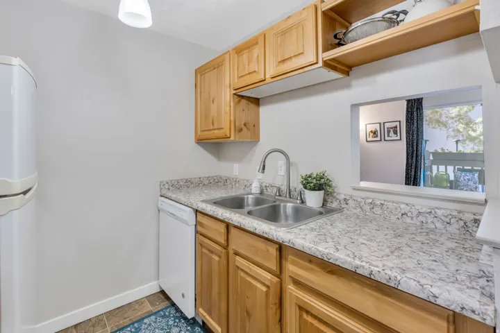 Kitchen featuring open shelves, white appliances, light countertops, and light wood finish cabinetry