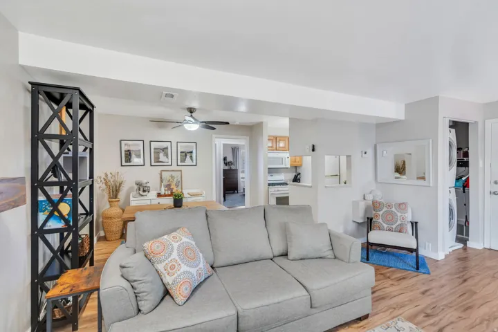 Living room featuring light wood finished floors, a ceiling fan, and stacked washing machine and dryer