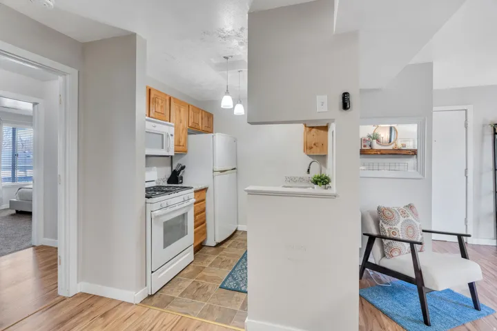 Kitchen with light countertops, white appliances, light wood-style flooring, decorative light fixtures, and light wood finish cabinets