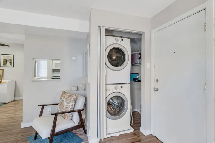 Laundry area featuring wood finished floors and stacked washer and dryer