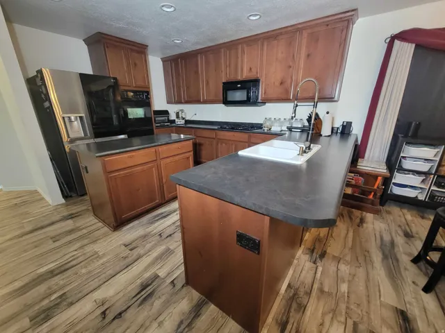 Kitchen with a center island, dark countertops, black appliances, a peninsula, and recessed lighting