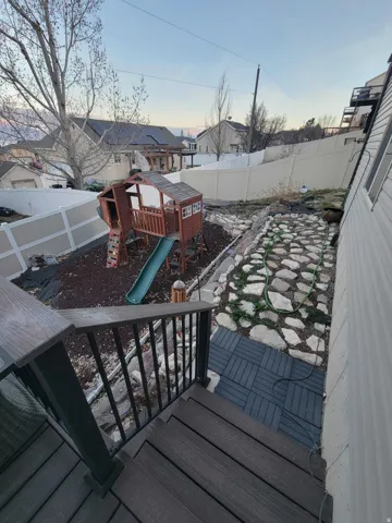 Partially fenced backyard featuring a playground, a