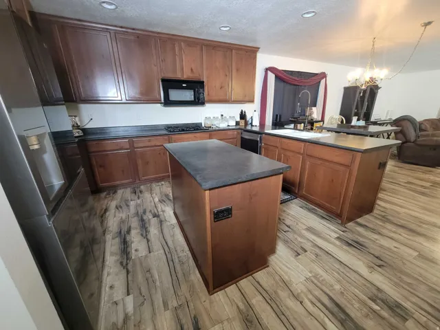 Kitchen with a peninsula, dark countertops, a center island, a chandelier, and open floor plan