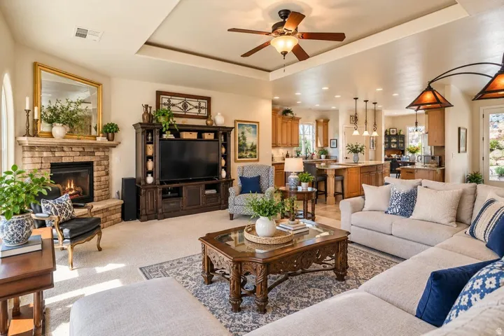 Living area featuring a stone fireplace, tray ceiling with a ceiling fan, and recessed lighting