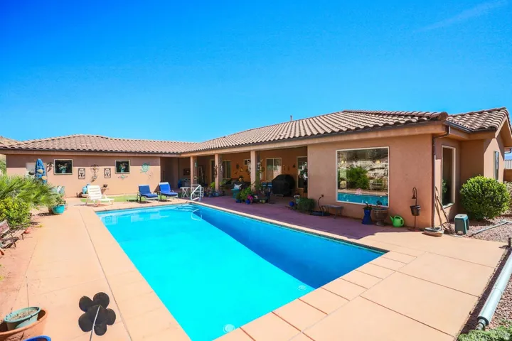 Outdoor swimming pool with a concrete patio, tile roof, stucco exterior, and covered patio