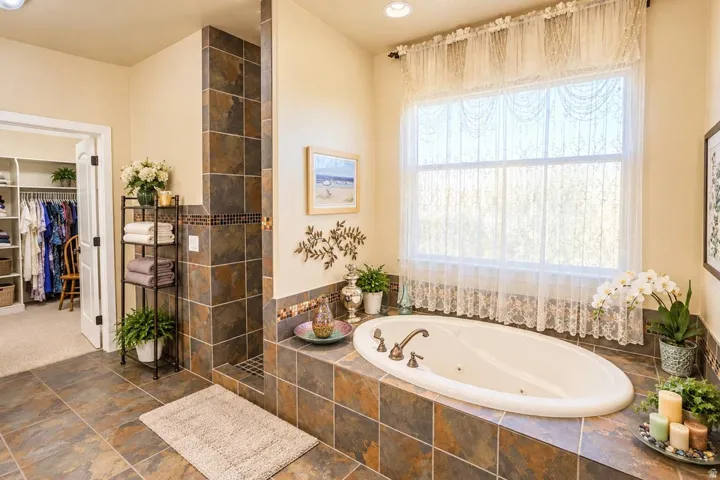 Spacious bathroom featuring an oval soaking tub, tiled surround, and walk-in shower with coordinating tile