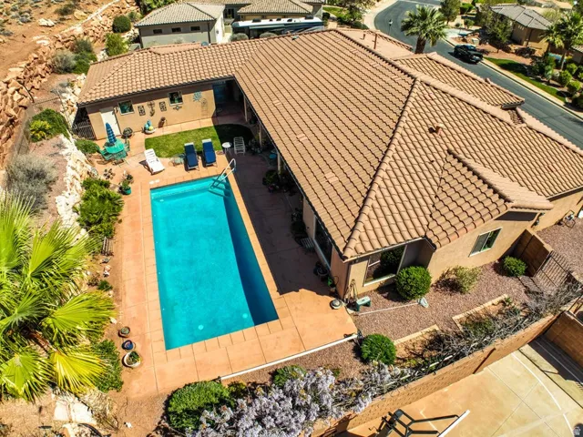 Exterior featuring a tile roof, stucco siding, a rectangular swimming pool, and a paved pool deck