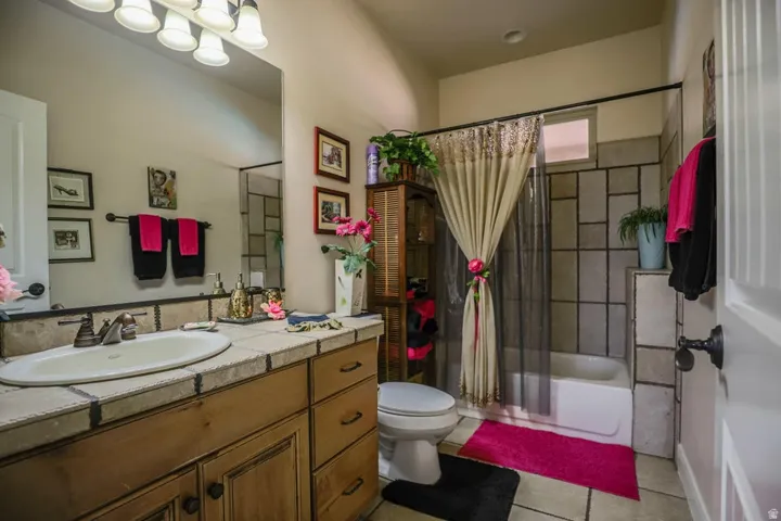 Vanity with a tiled countertop, undermount sink, and bronze-finish faucet