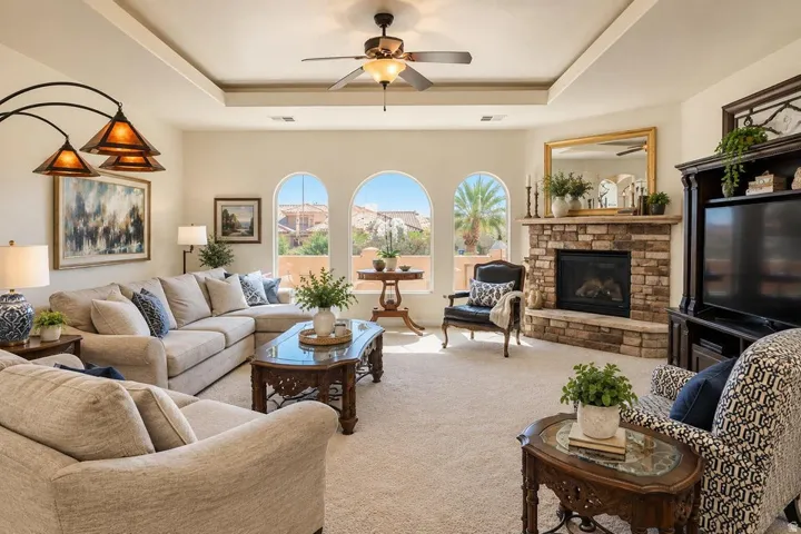 Spacious living area featuring a stone-clad fireplace, coffered ceiling, and arched windows