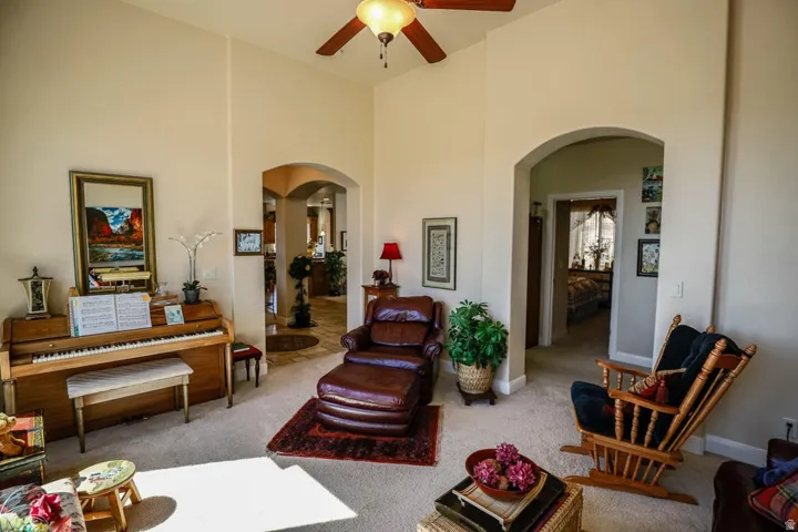 Vaulted ceilings with a ceiling fan, arched doorways, and carpeted flooring
