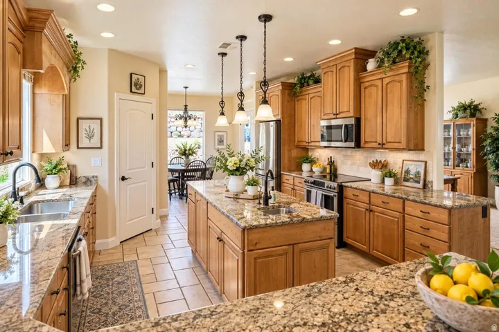 Spacious kitchen featuring extensive wood cabinetry, granite countertops, a central island with a sink, stainless steel appliances, and recessed lighting