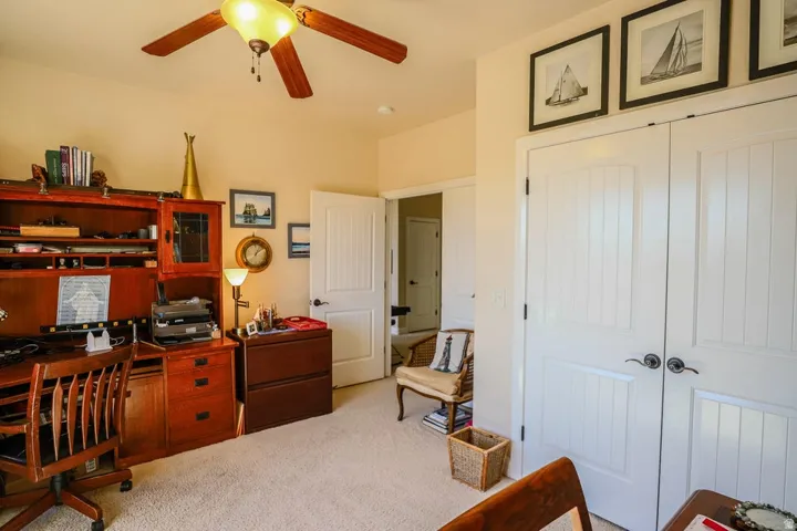 Carpeted room featuring a ceiling fan with integrated lighting, built-in wooden shelving, and panel doors