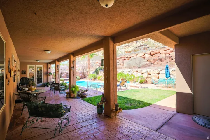 Covered patio with stamped concrete flooring, direct access to a swimming pool, and a landscaped backyard