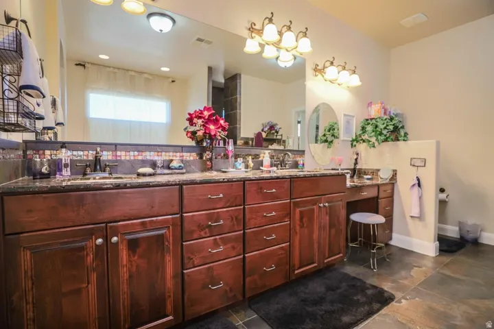 Dual vanity with dark wood cabinetry, integrated sinks, and a stone countertop