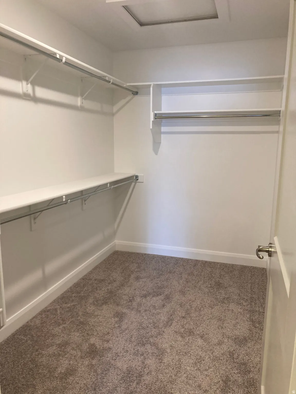 MODEL Walk in closet with attic access and dark colored carpet