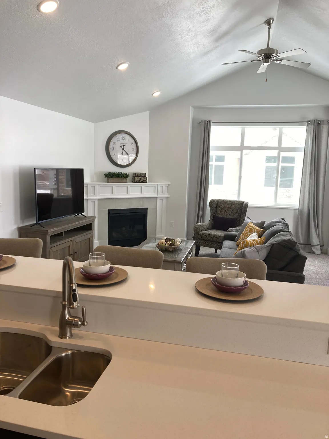 MODEL Kitchen featuring open floor plan, a tiled fireplace, a ceiling fan, recessed lighting, and a textured ceiling