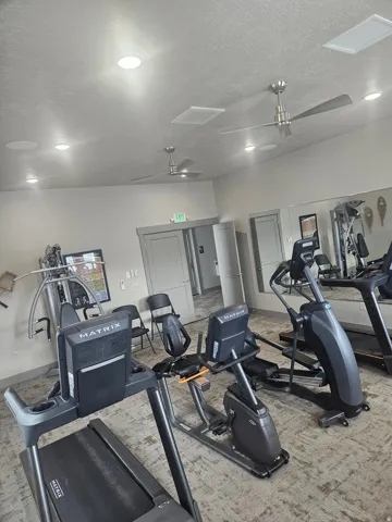 CLUBHOUSE Exercise room with ceiling fan and a textured ceiling