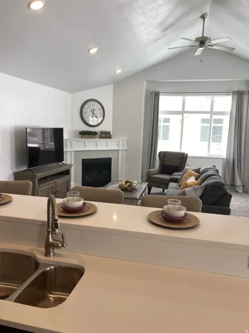 MODEL Kitchen featuring open floor plan, a tiled fireplace, a ceiling fan, recessed lighting, and a textured ceiling