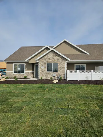 View of front facade featuring stucco siding, stone siding, and a shingled roof