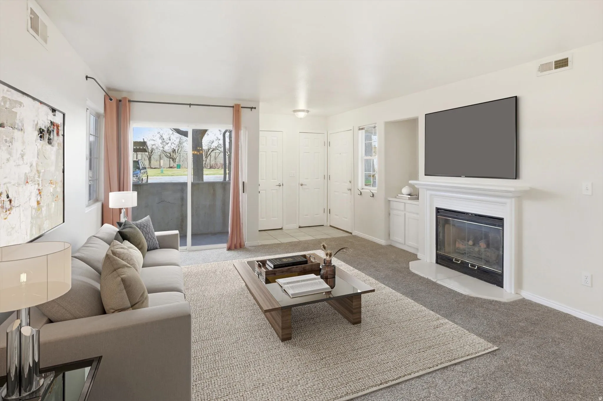 Living room with light carpet and a glass covered fireplace