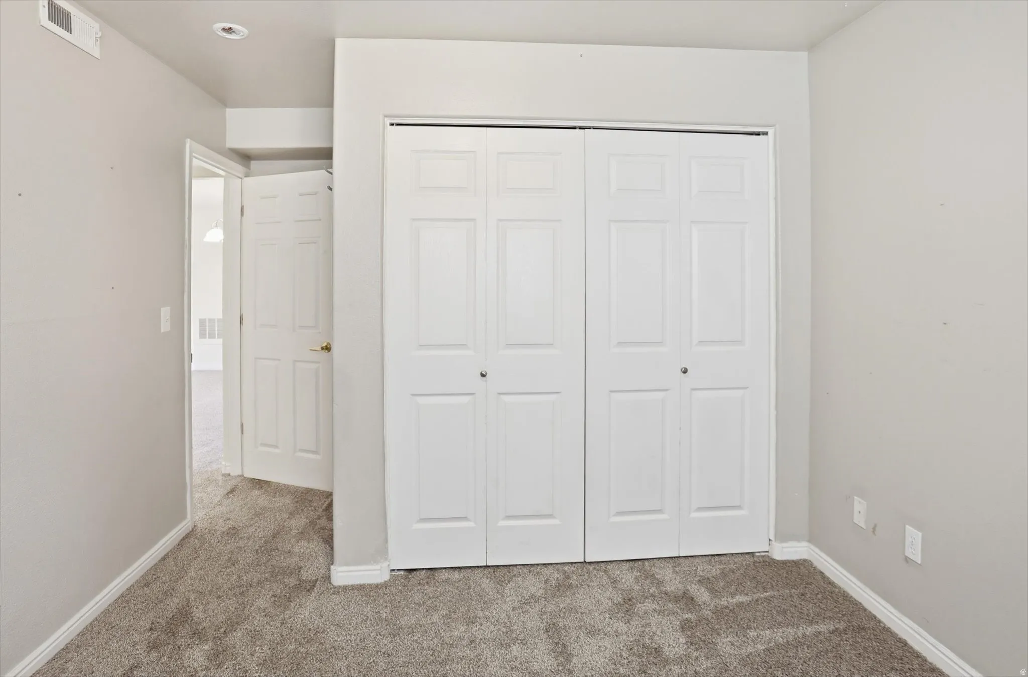 Unfurnished bedroom with light colored carpet and a closet
