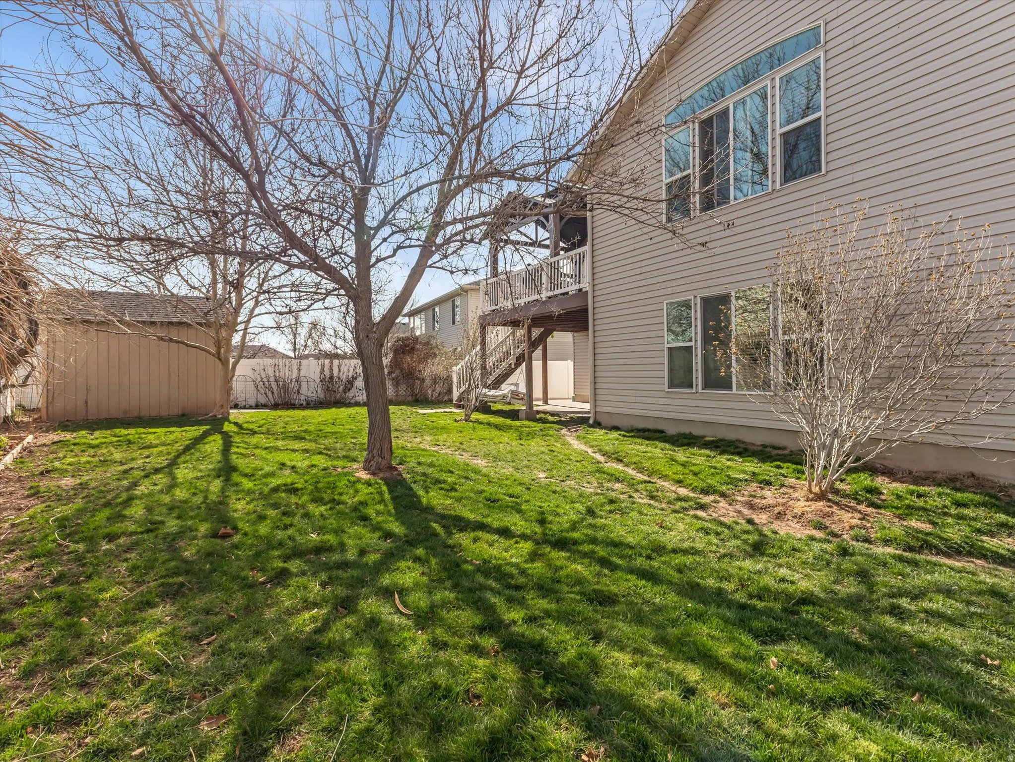 View of grassy yard with a deck and an outdoor structure